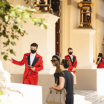 red coat greeting visitors